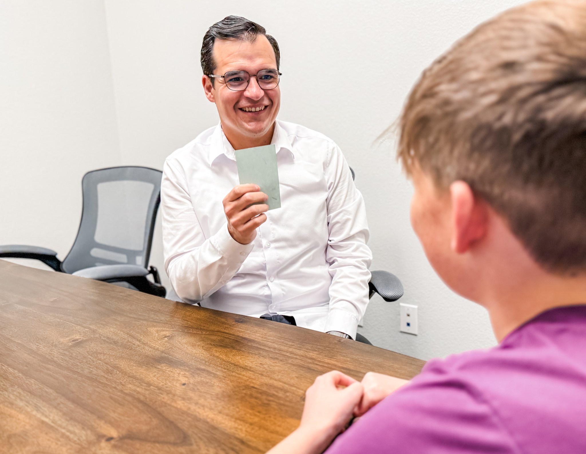 Michael working one-on-one with a student, using flashcard-style reading materials at a table