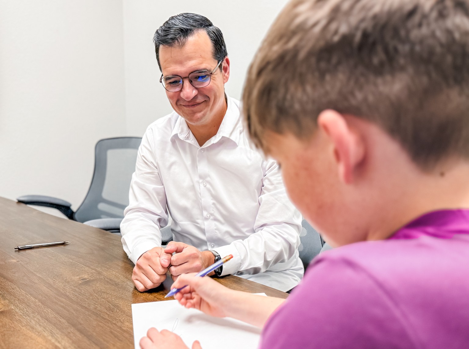 Michael guiding a student through a handwriting exercise at the table